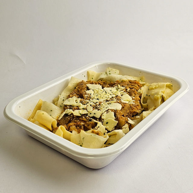 Pasta dish with meat and cheese in a white container on a light gray background
