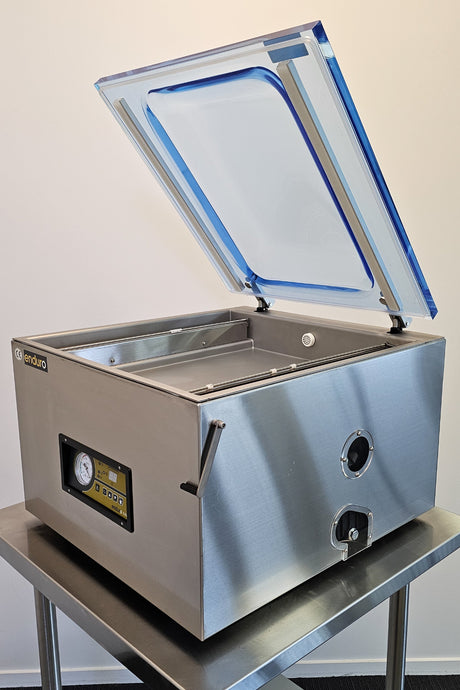 Stainless steel vacuum sealer on a stand with a plain background