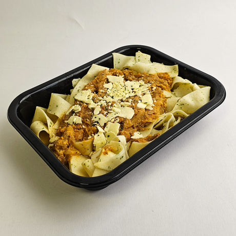 Pasta dish with sauce and cheese in a black container on a white background
