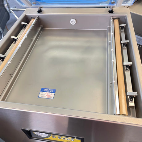 Stainless steel vacuum packaging machine with a visible certification label.