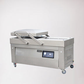 A floor-standing, double chamber gas-flush vacuum packaging machine with a digital display, control panel, and set on mobility castors.