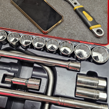 Socket set with tool organizer on a gray surface, including a smartphone and screwdriver.